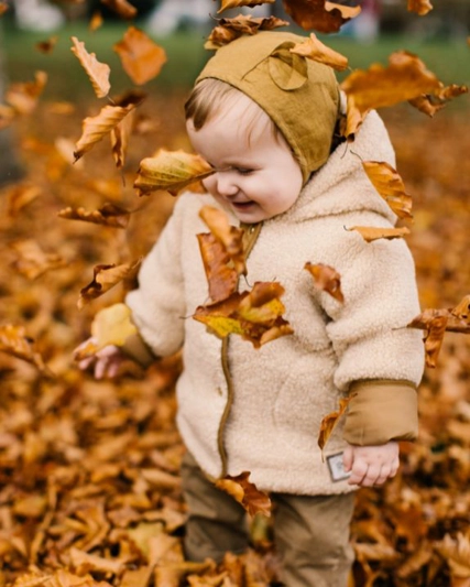 Kleinkind in Herbstlaub stehend